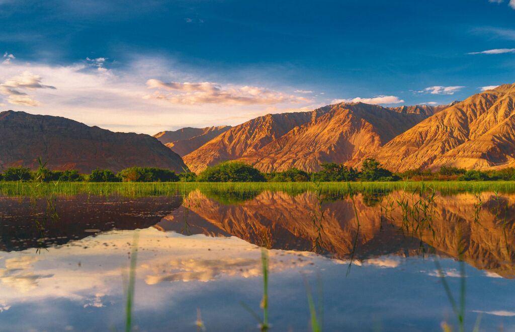 brown mountain beside lake under blue sky during daytime
